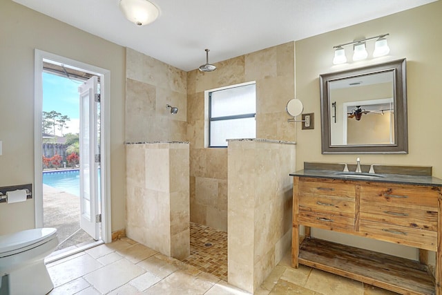 bathroom with a tile shower, vanity, and toilet