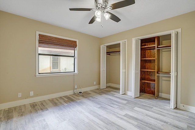 unfurnished bedroom featuring light wood-type flooring, ceiling fan, and multiple closets