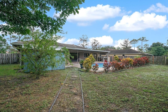 back of property featuring a fenced in pool and a yard