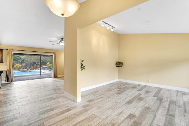 spare room featuring ceiling fan, rail lighting, vaulted ceiling, and light wood-type flooring