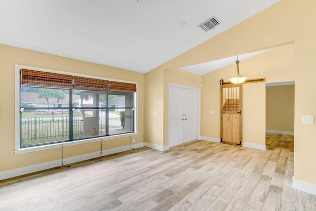 unfurnished room with light hardwood / wood-style floors and vaulted ceiling