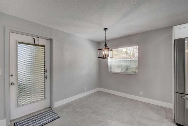 632 Monaco N, Delray Beach, FL 33446 - unfurnished dining area with a chandelier, a textured ceiling, and baseboards