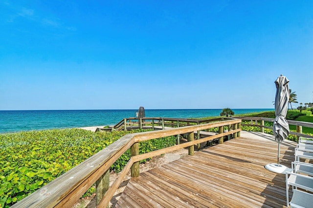 wooden terrace featuring a water view and a beach view