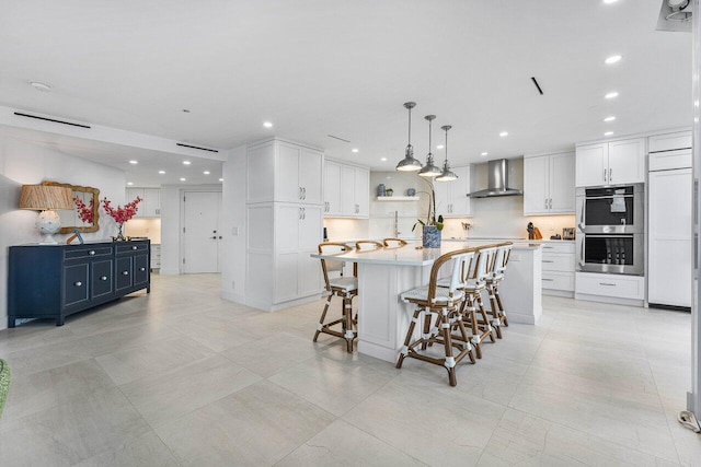 kitchen with a spacious island, wall chimney exhaust hood, blue cabinets, and stainless steel double oven