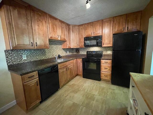 kitchen featuring sink, black appliances, decorative backsplash, and a textured ceiling