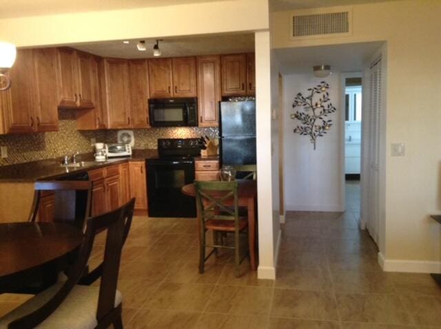 kitchen with backsplash, black appliances, and dark tile patterned floors