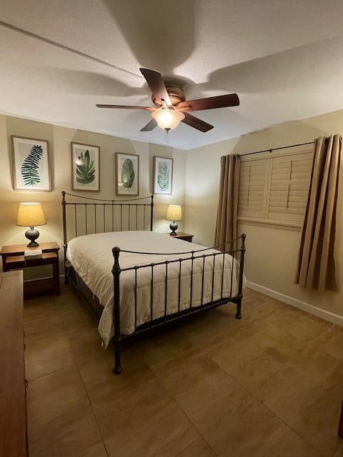 bedroom with dark tile patterned flooring and ceiling fan