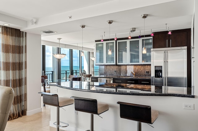 kitchen with appliances with stainless steel finishes, dark brown cabinetry, a water view, and dark stone counters