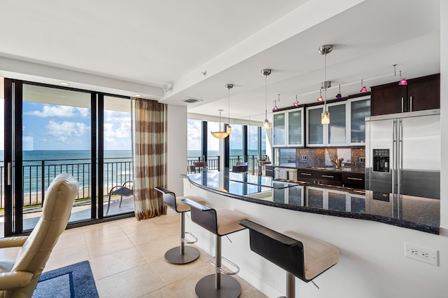 kitchen featuring appliances with stainless steel finishes, a kitchen bar, backsplash, dark brown cabinetry, and a water view