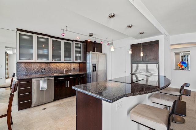 kitchen featuring sink, dark brown cabinets, stainless steel appliances, decorative light fixtures, and decorative backsplash