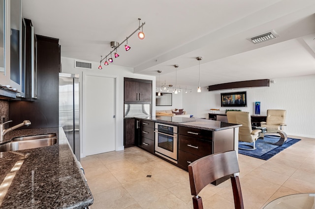 kitchen with dark brown cabinets, appliances with stainless steel finishes, sink, and decorative light fixtures