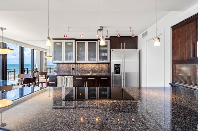 kitchen featuring decorative backsplash, hanging light fixtures, stainless steel appliances, dark brown cabinets, and a water view