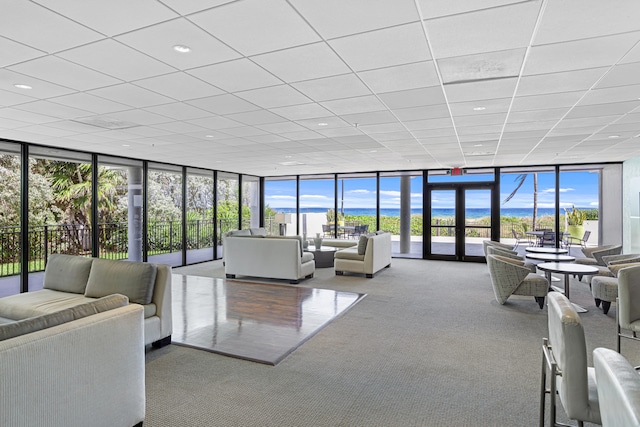 living room with carpet, a water view, and floor to ceiling windows