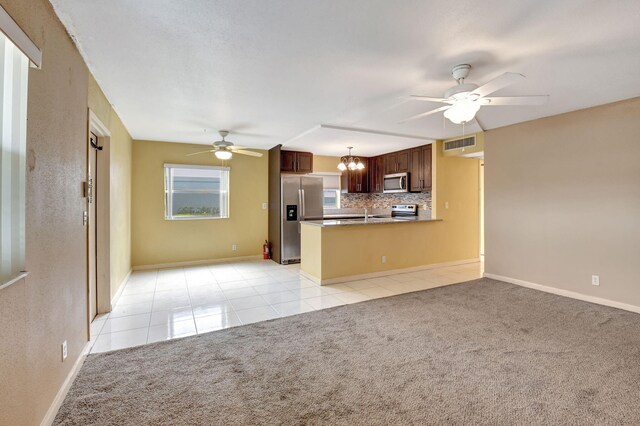 unfurnished living room featuring ceiling fan with notable chandelier and light tile patterned floors