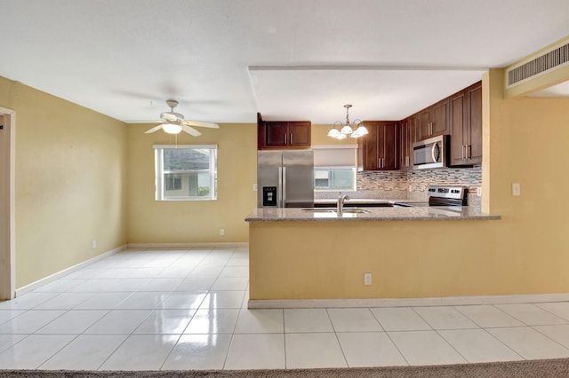 kitchen with decorative light fixtures, tasteful backsplash, sink, kitchen peninsula, and stainless steel appliances