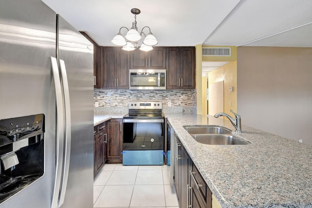 kitchen featuring dark brown cabinetry, sink, stainless steel appliances, light stone countertops, and decorative backsplash