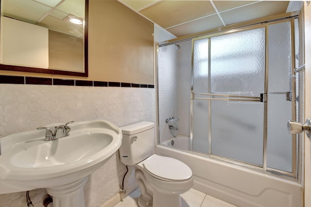 full bathroom with toilet, sink, shower / bath combination with glass door, tile walls, and tile patterned flooring