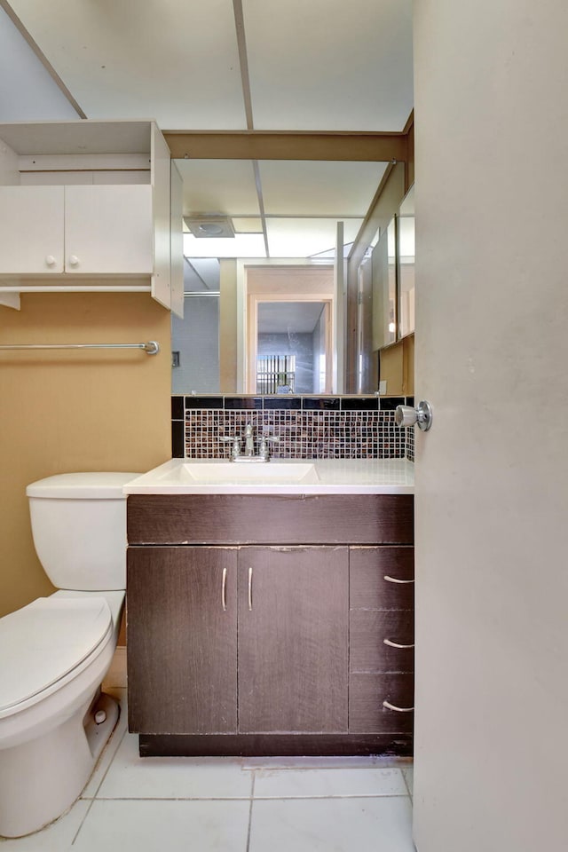 bathroom with tasteful backsplash, tile patterned floors, toilet, and vanity