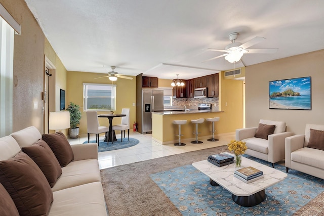 tiled living room featuring ceiling fan with notable chandelier