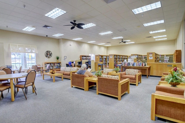 living room featuring light colored carpet, a drop ceiling, and ceiling fan