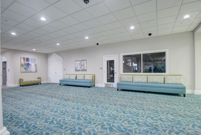 unfurnished living room featuring carpet and a drop ceiling