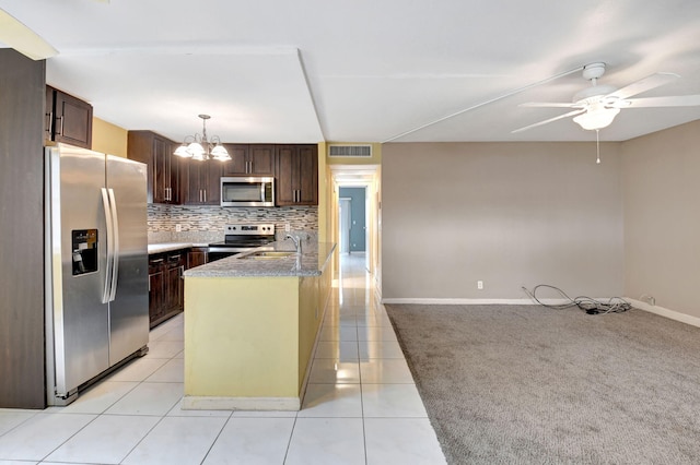 kitchen with dark brown cabinetry, light tile patterned floors, decorative light fixtures, and stainless steel appliances