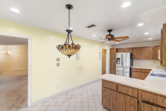 kitchen with stainless steel appliances, kitchen peninsula, light colored carpet, decorative light fixtures, and ceiling fan with notable chandelier