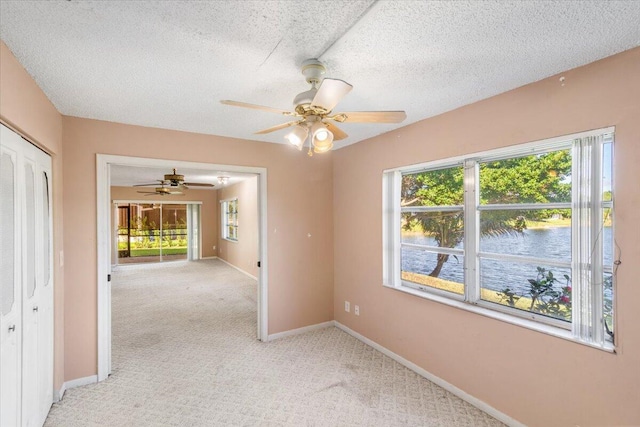 carpeted spare room featuring ceiling fan, a healthy amount of sunlight, and a textured ceiling