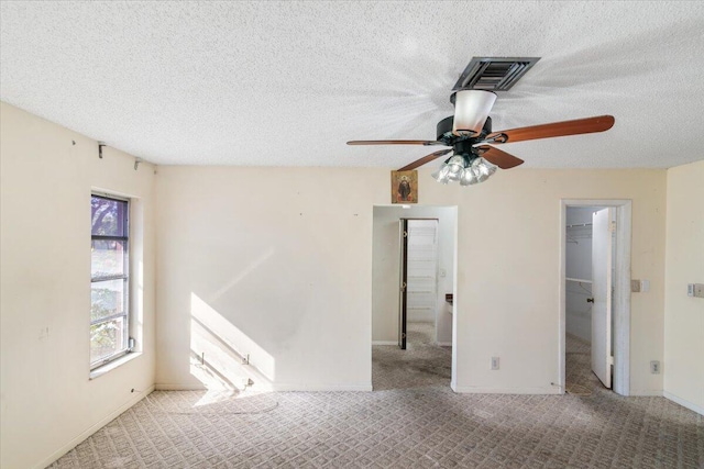 interior space with a textured ceiling, light colored carpet, a spacious closet, and ceiling fan