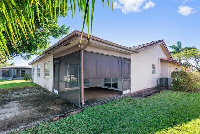 view of property exterior featuring a sunroom, a yard, and cooling unit