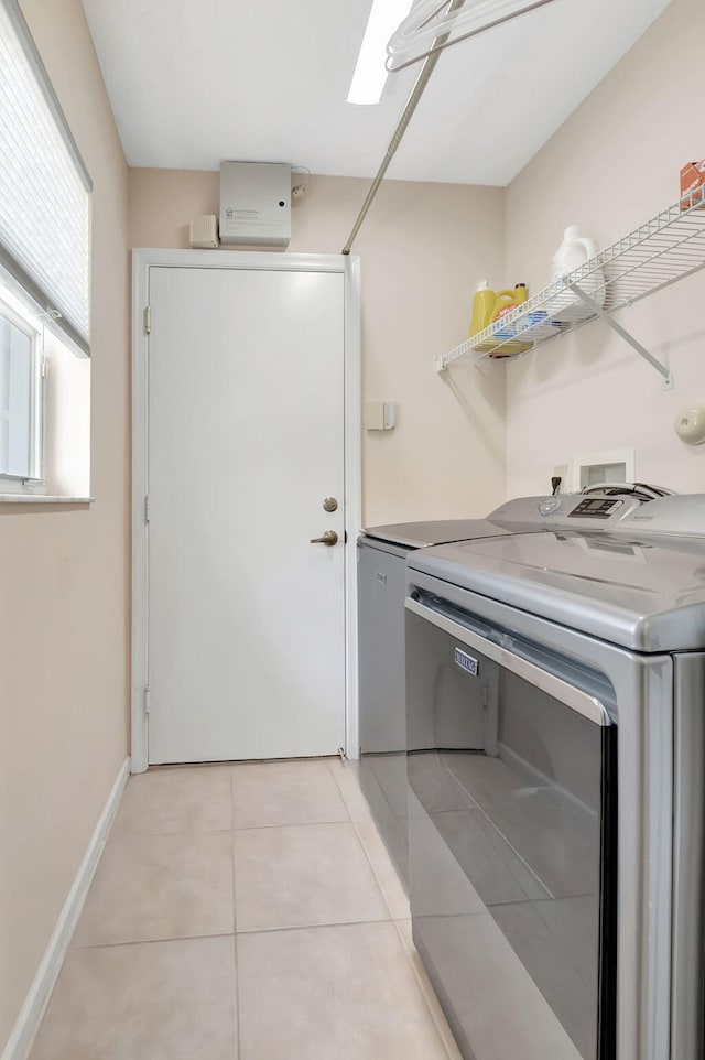 clothes washing area with light tile patterned floors and washer and dryer