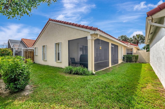 rear view of property with a yard and a sunroom