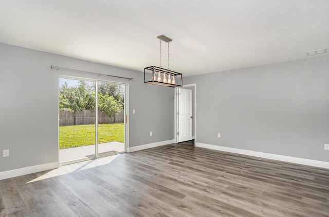 unfurnished dining area with hardwood / wood-style floors and a textured ceiling