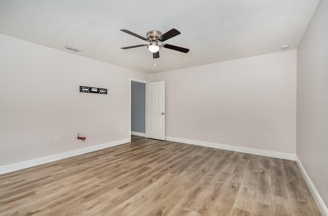 unfurnished room with a textured ceiling, light wood-type flooring, and ceiling fan