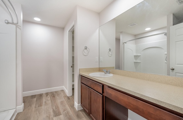 bathroom featuring walk in shower, hardwood / wood-style floors, and vanity