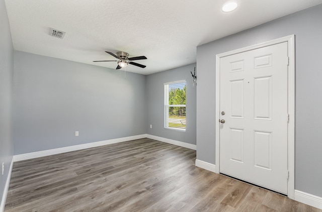 entryway with a textured ceiling, ceiling fan, and light hardwood / wood-style flooring