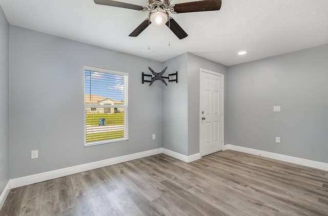 empty room with ceiling fan, a textured ceiling, and light wood-type flooring