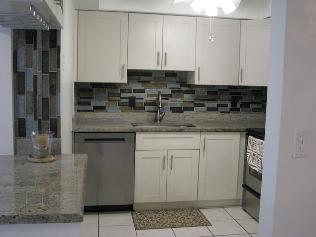 kitchen with tasteful backsplash, dark stone counters, stainless steel appliances, sink, and white cabinets