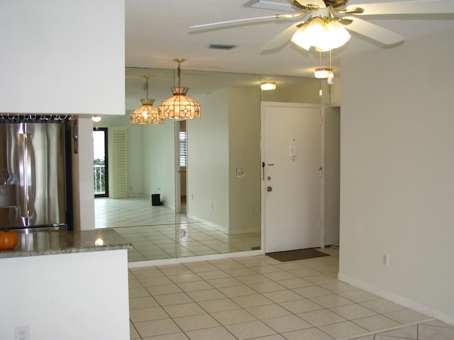 kitchen featuring ceiling fan, stainless steel fridge with ice dispenser, hanging light fixtures, and light tile patterned floors