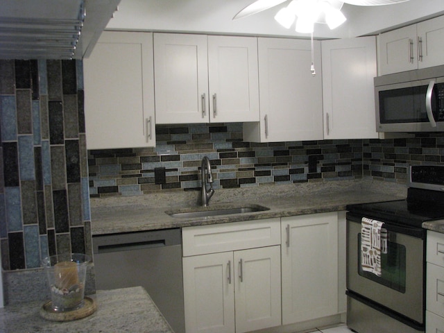 kitchen with sink, stainless steel appliances, tasteful backsplash, dark stone countertops, and white cabinets