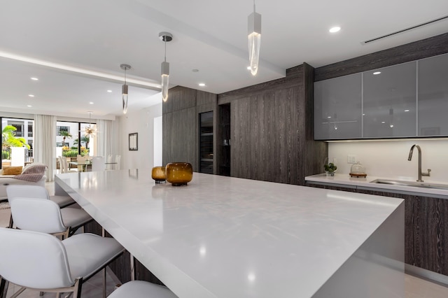 kitchen featuring pendant lighting, a breakfast bar, dark brown cabinets, and sink