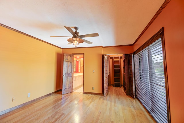 unfurnished bedroom with ensuite bathroom, crown molding, ceiling fan, light wood-type flooring, and a closet