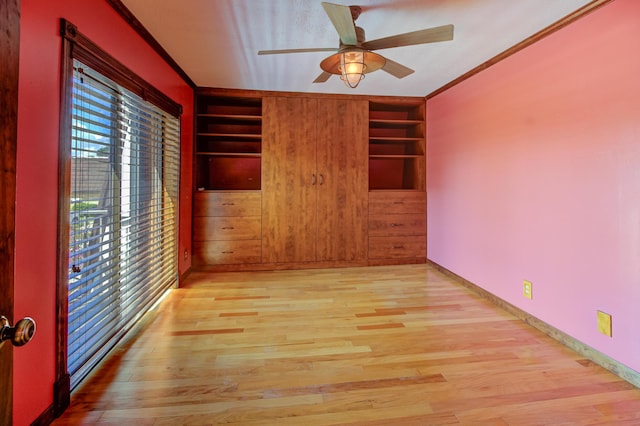 unfurnished room featuring ceiling fan, built in features, wood walls, light hardwood / wood-style floors, and ornamental molding