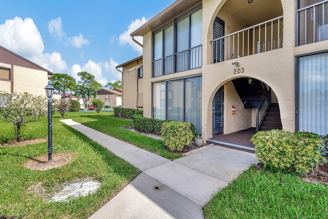 property entrance with a balcony and a lawn