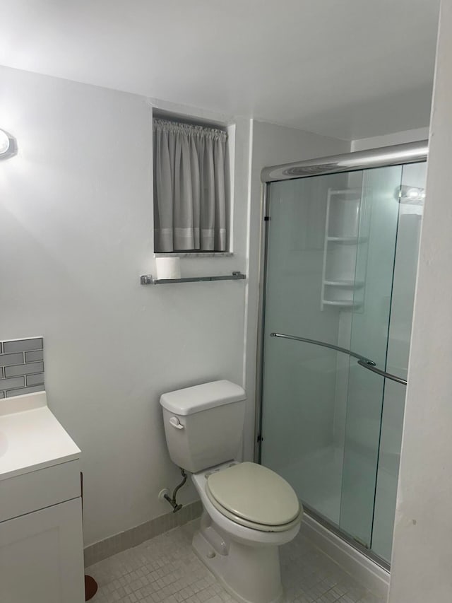 bathroom featuring vanity, toilet, a shower with shower door, and tile patterned flooring