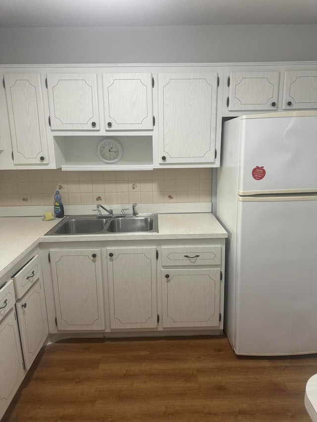 kitchen with tasteful backsplash, white cabinetry, dark wood-type flooring, sink, and white refrigerator