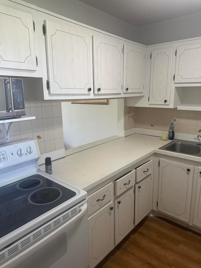 kitchen with white electric range oven, sink, dark wood-type flooring, and decorative backsplash