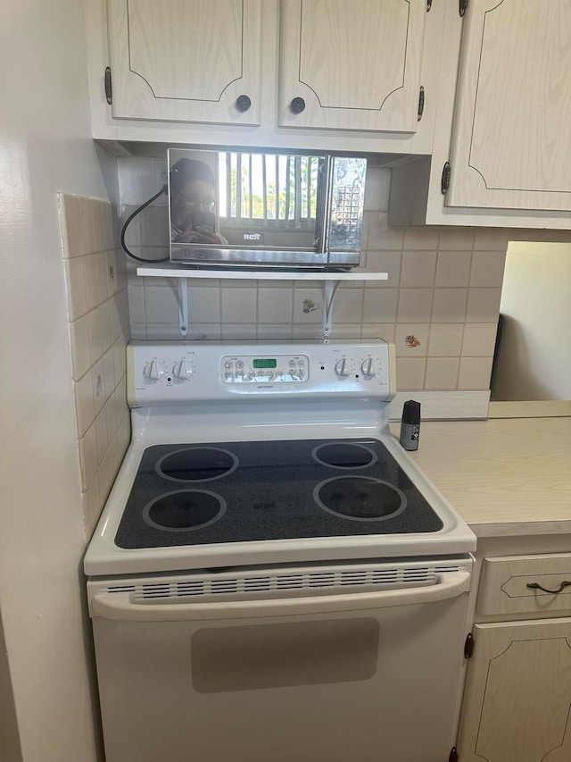 kitchen featuring electric range, backsplash, and light brown cabinets