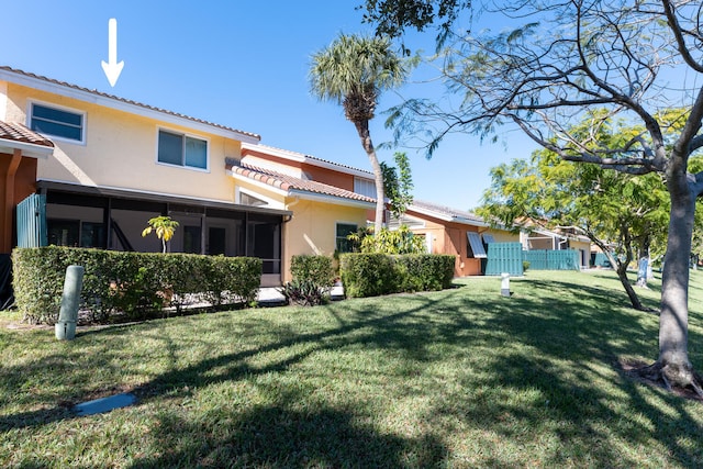 rear view of house with a sunroom and a yard