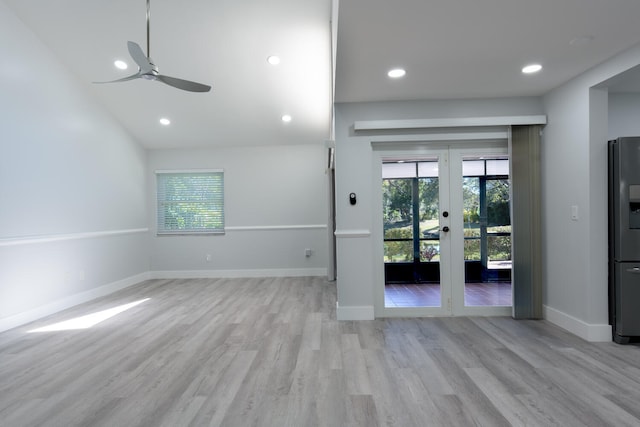 unfurnished living room featuring light wood-type flooring, vaulted ceiling, ceiling fan, and french doors